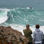 a group of people watching a surfer ride a wave