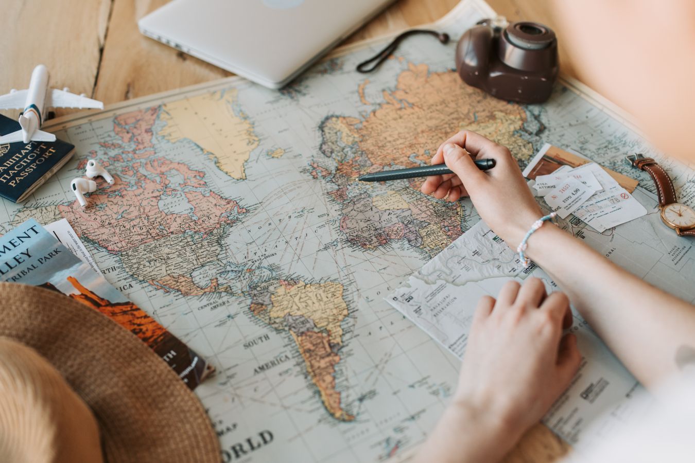 Mains marquant des destinations sur une carte du monde pour organiser un voyage
