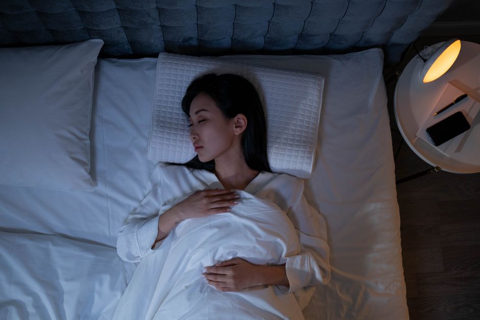 Femme endormie paisiblement dans son lit, profitant d'une heure de sommeil en plus à l'heure d'hiver